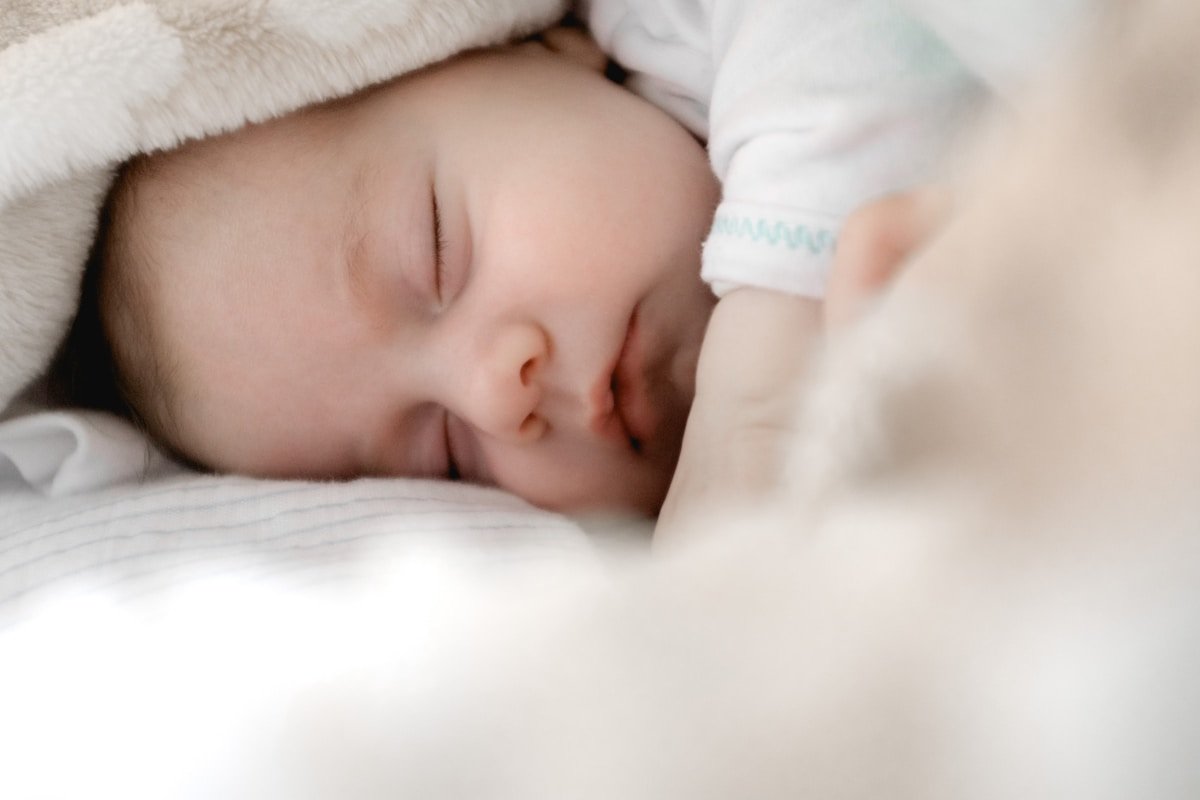Bebê dormindo profundamente e confortável no berço com luz suave e quente